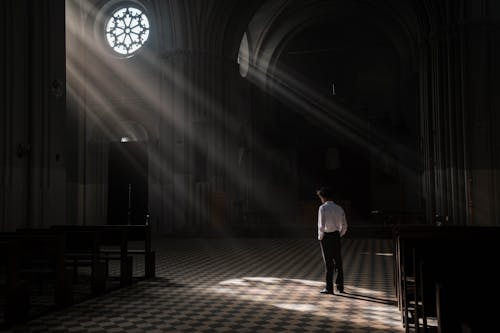 A Person Standing Inside the Church Aisle
