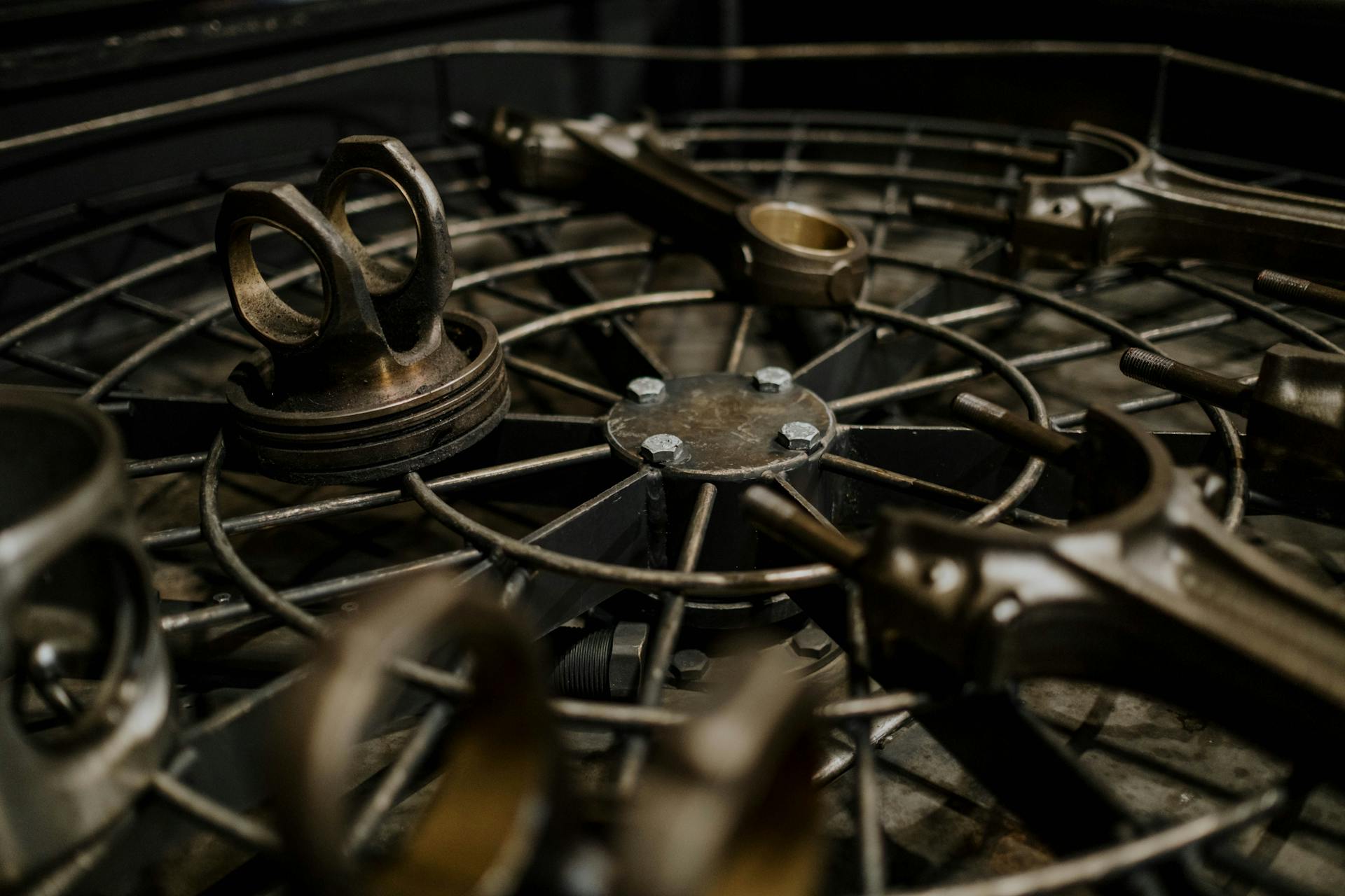 Detailed view of rusted metal car parts on grid, indicating garage atmosphere.