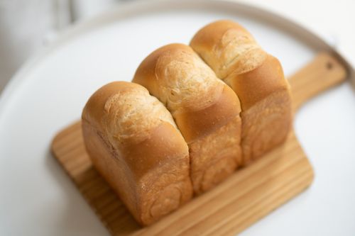 Free Close-up of a golden loaf of bread on a wooden board, perfect for food-related projects. Stock Photo