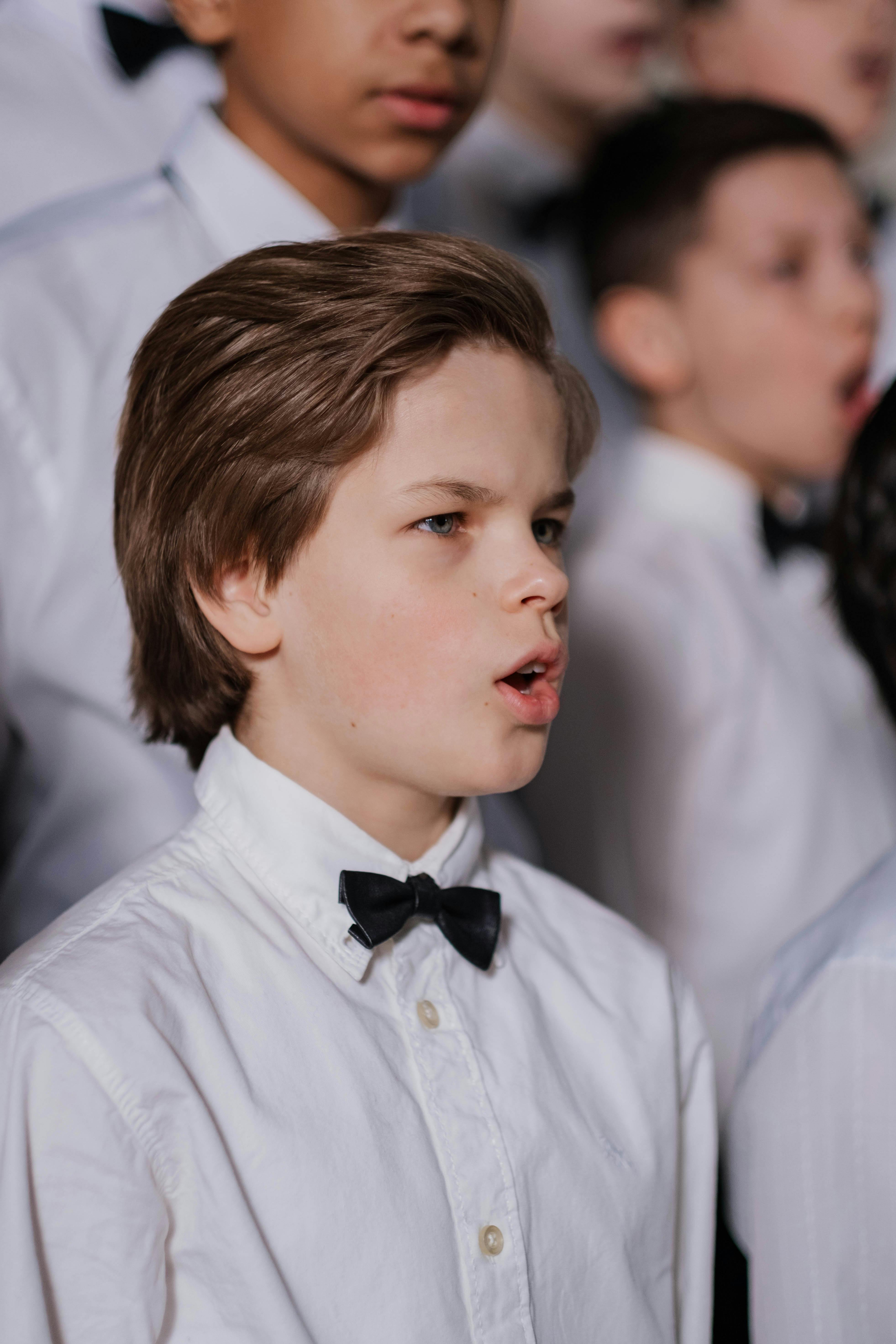 boy in white shirt and black bowtie singing