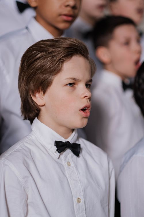 Free Portrait of young choir boys dressed in uniforms singing passionately in a performance. Stock Photo