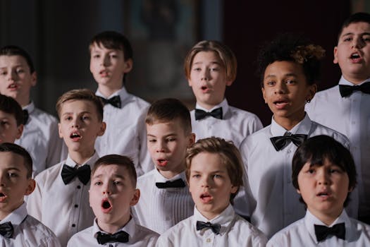 Group of boys performing in a choir, dressed in white shirts and black bowties.