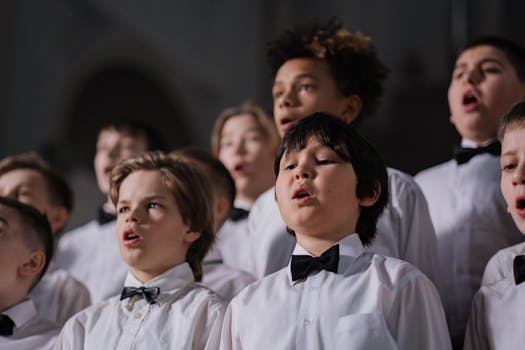 A group of boys in white shirts and bow ties performing in a choir.