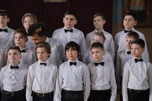 Free A group of boys dressed in white shirts and bowties performing in a choir indoors, showcasing diversity and unity. Stock Photo