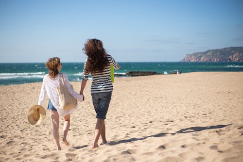 A Couple Holding Hands while Walking on the Seashore