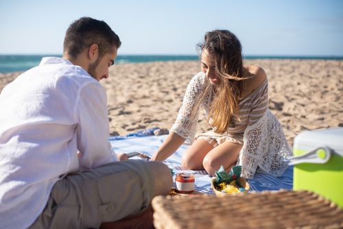 Free A couple enjoys a sunny picnic on a beach in Portugal, capturing a moment of togetherness. Stock Photo