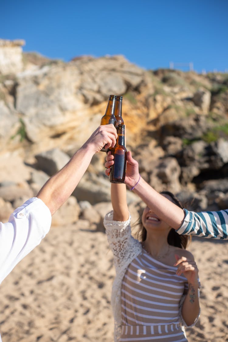 A Group Of Friends Raising Hands While Toasting Their Beer Bottles