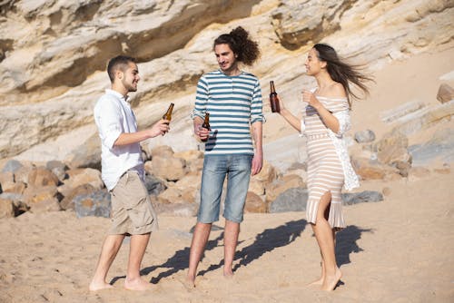 Free Men and a Woman Drinking Beer in the Beach Stock Photo