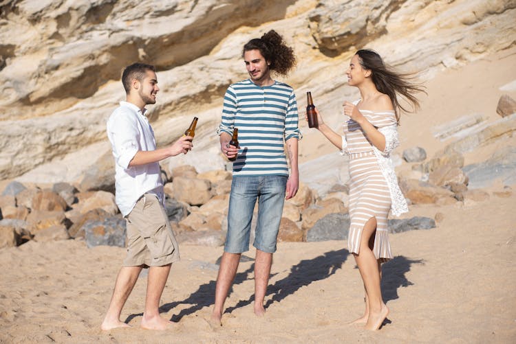 Men And A Woman Drinking Beer In The Beach