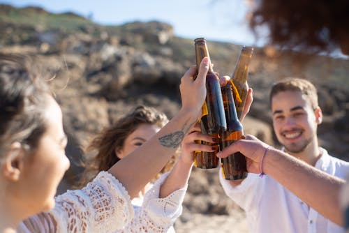 Group of Friends Clinking Beer Bottles and Smiling 