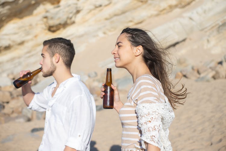 A Couple Drinking Beer On The Beach