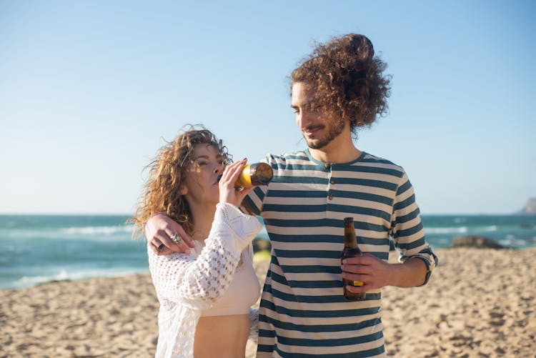 Couple Drinking Beer On Beach