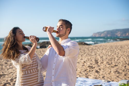 A Couple Drinking Beers on Bottle in the Beach