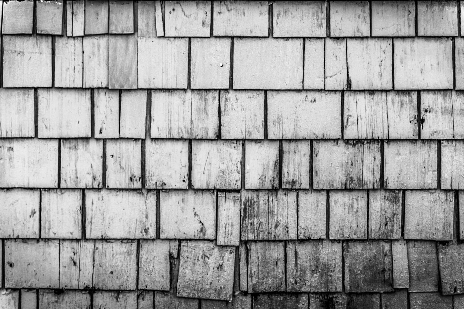 A detailed black and white image showcasing a rustic wooden shingle wall texture.