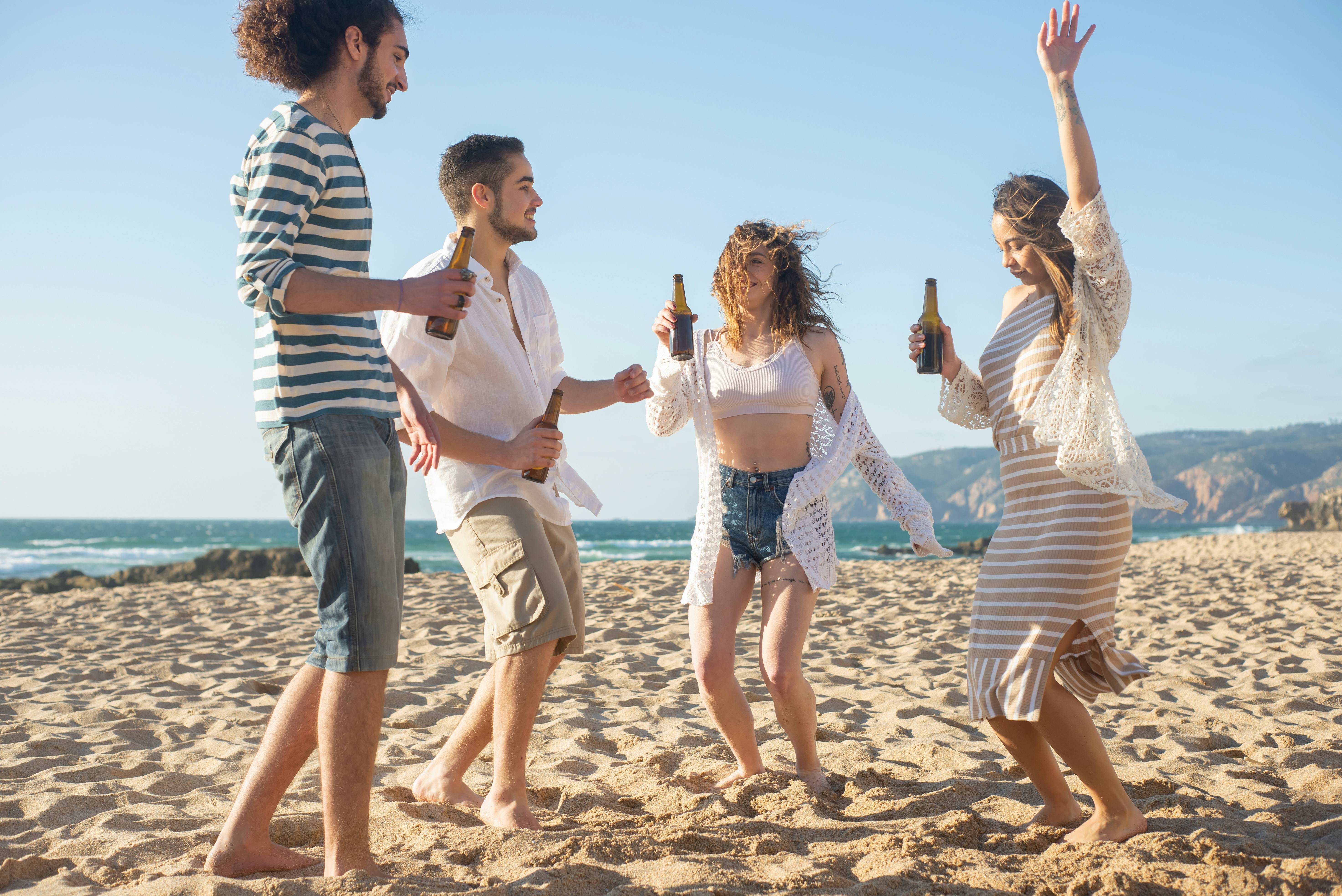 一群朋友在葡萄牙阳光明媚的海滩上玩耍，跳舞和享受饮料