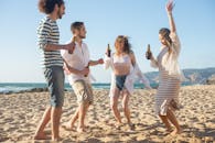 一群朋友在葡萄牙阳光明媚的海滩上玩耍，跳舞和享受饮料