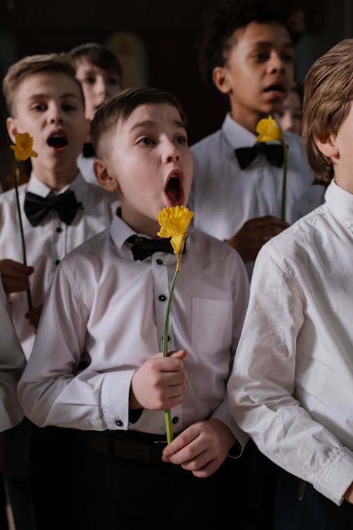 Boy Holding Yellow Flower While Singing