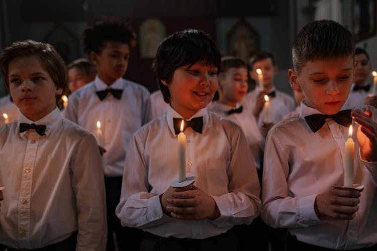 Boys In White Shirt And Bowtie Holding A Lighted Candle