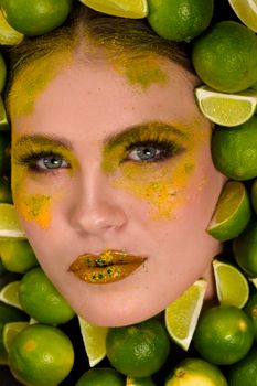 Artistic makeup portrait surrounded by fresh limes, highlighting vivid colors and creativity.