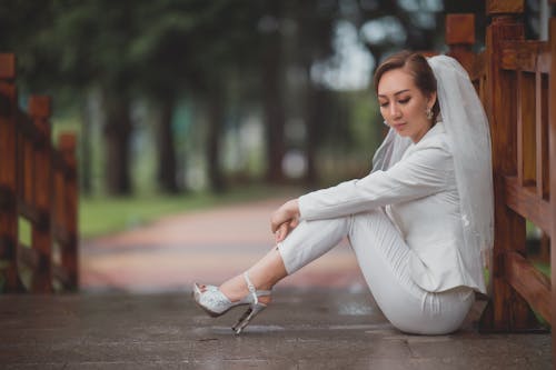 Woman in White Long Sleeve Shirt and White Pants with Veil Sitting on Tiled Floor