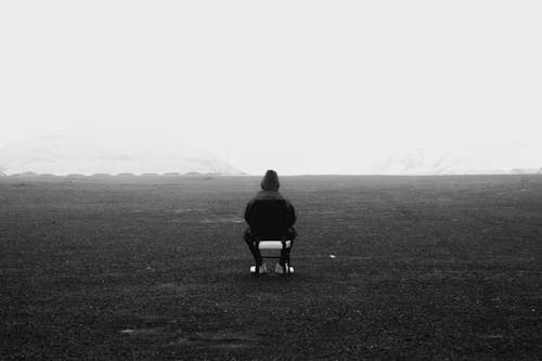 Person in Hoody Sitting on Chair 