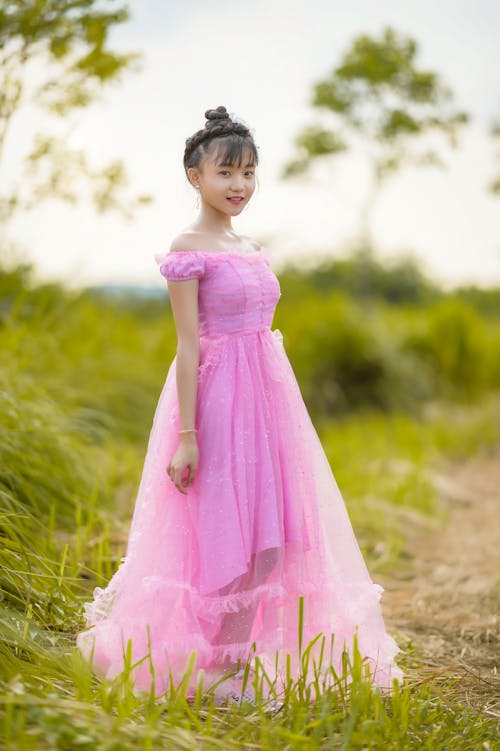 A Girl in Pink Dress Standing on the Field