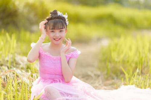 A Girl in Pink Dress Sitting on the Field