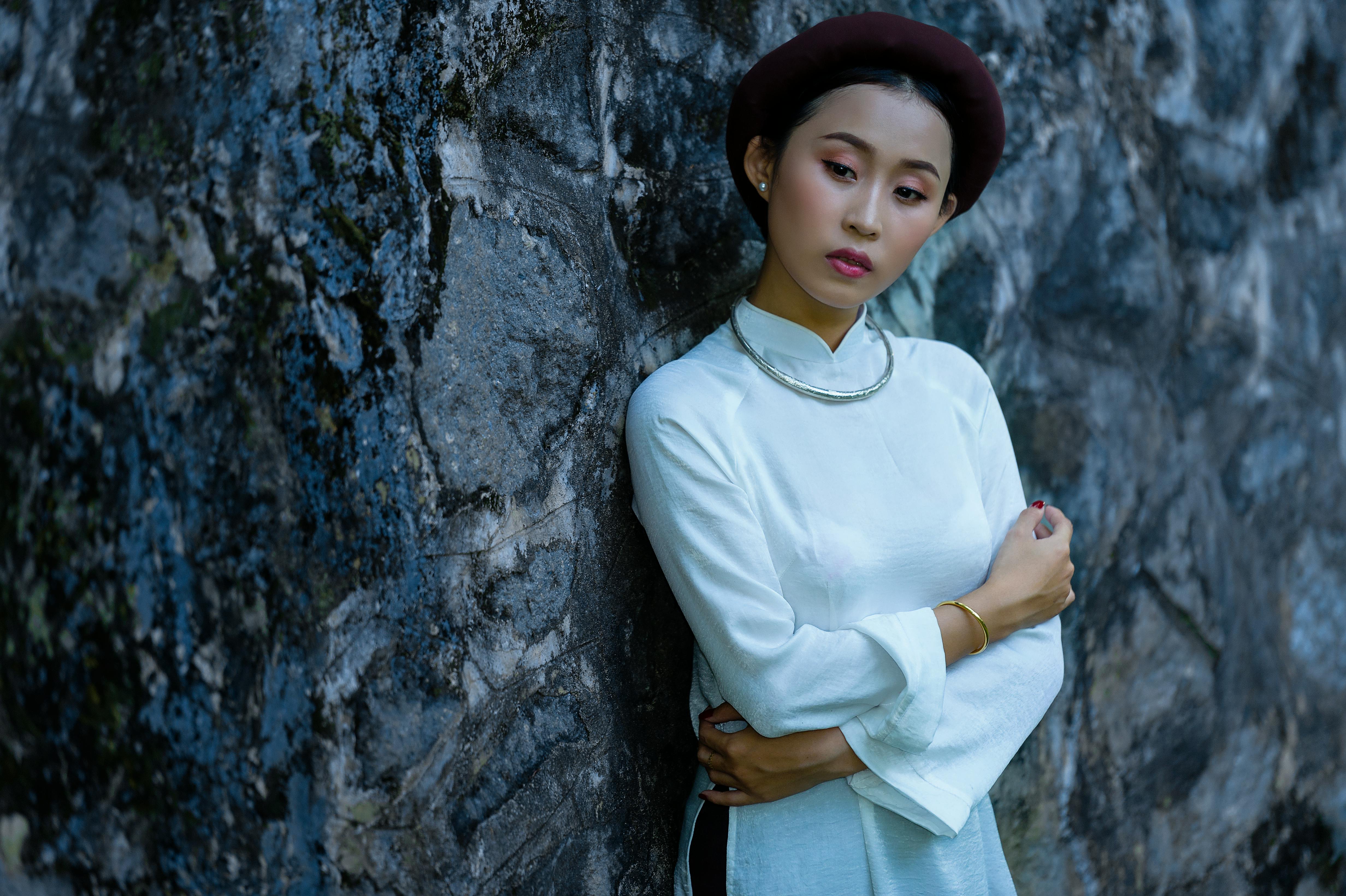 a beautiful woman leaning on a rocky wall