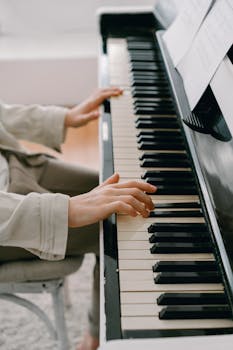 Hands playing piano with sheet music indoors, focusing on musical aesthetics.