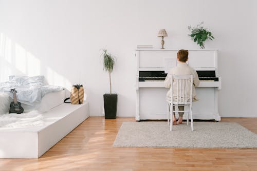 A Back View of a Person Sitting while Playing Piano