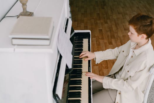 Young boy skillfully playing the piano, focusing on music notes in a bright indoor setting.