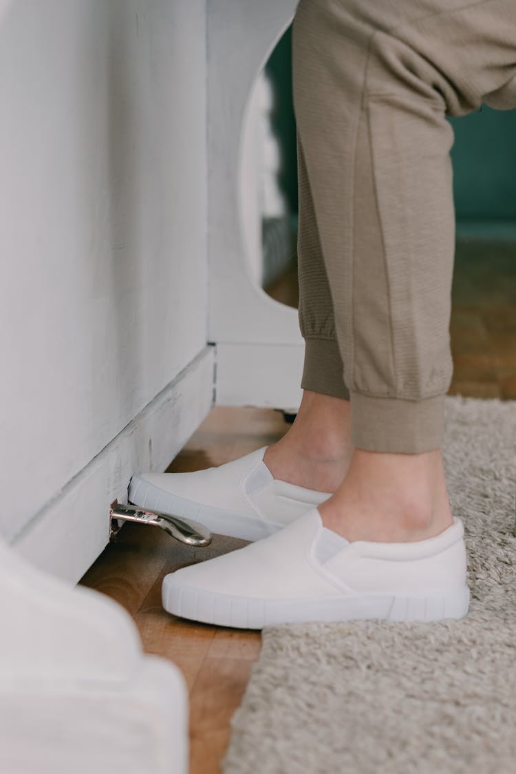 A Person In Brown Pants Wearing White Shoes While Stepping On A Pedal