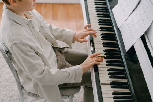 Free A young person playing piano with a music sheet, focusing on the keys and hands. Stock Photo
