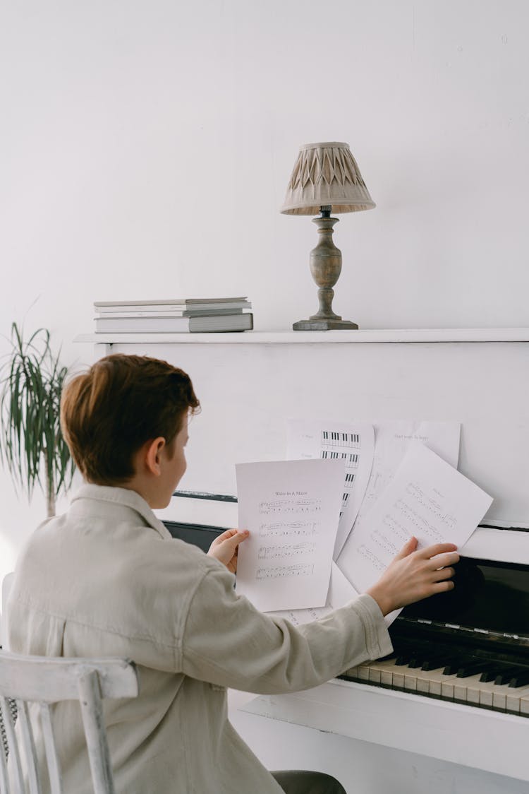 Boy Sitting By The Piano Reading Music Sheets