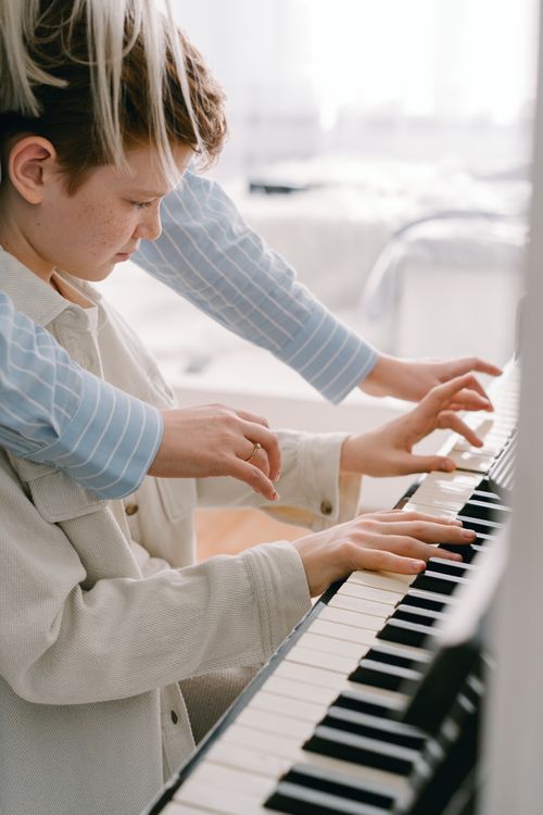 Free A student receives guidance from a teacher while learning to play the piano indoors. Stock Photo