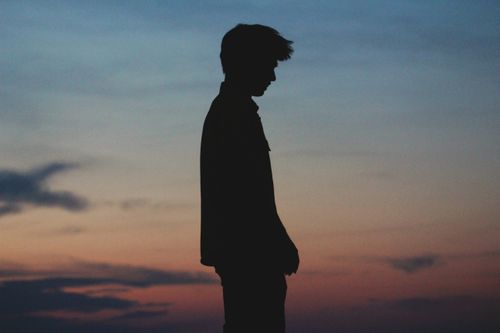 Free A captivating silhouette of a man standing against a colorful twilight sky. Stock Photo