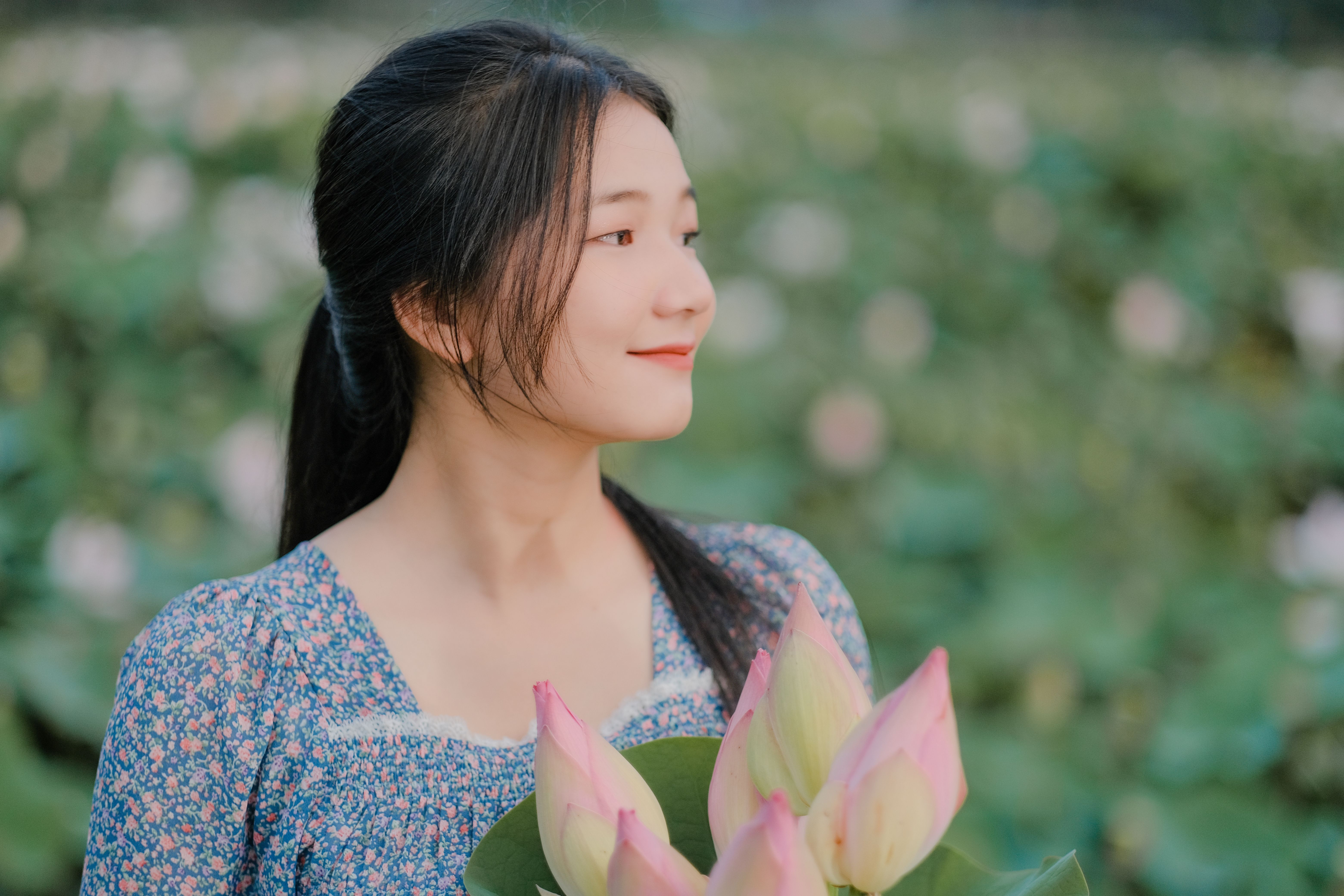 A Woman in Floral Shirt Smiling while Holding Flowers · Free Stock Photo