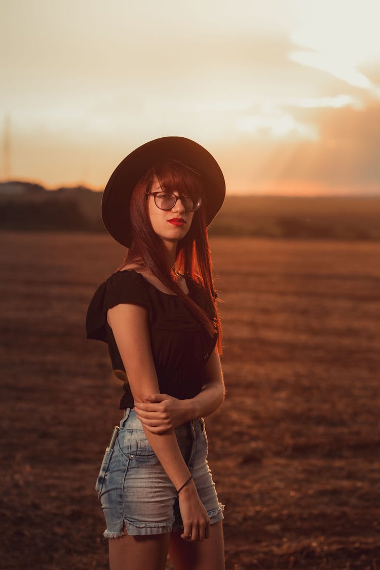 Woman In Black Shirt And Blue Denim Shorts Wearing Black Sun Hat 