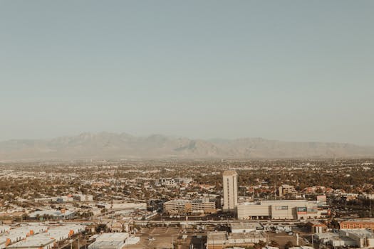 Aerial photo showcasing a city's urban sprawl against a mountain backdrop during daytime.