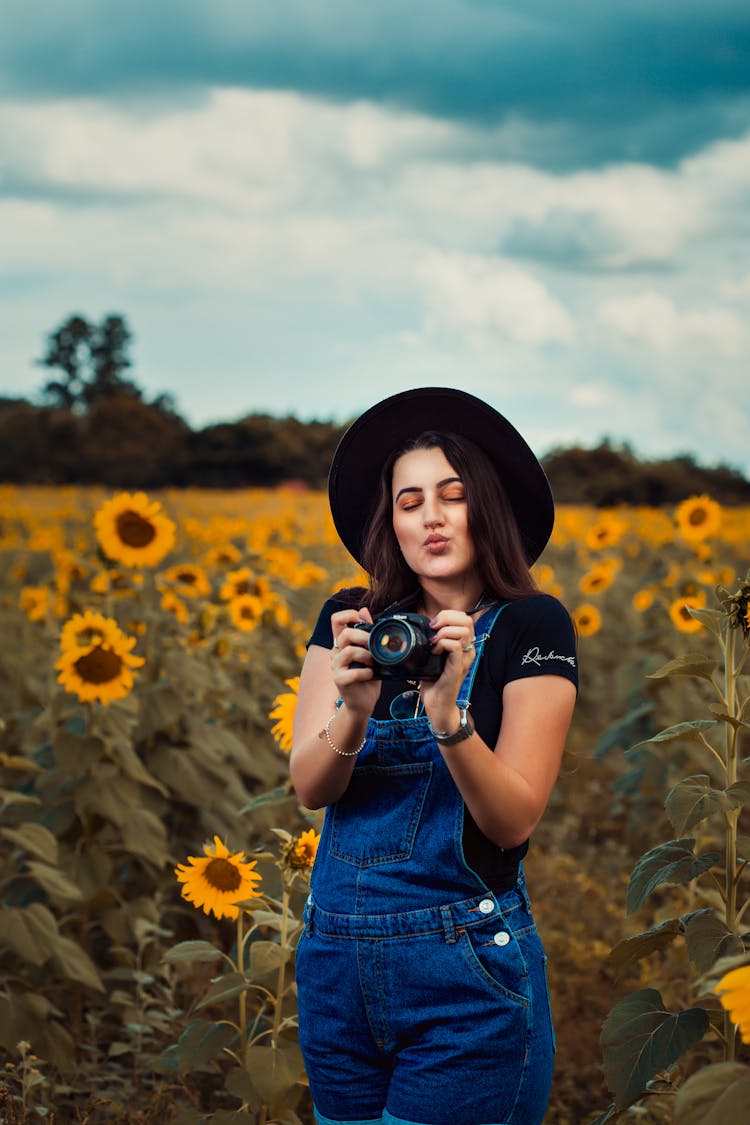 Woman On Sunflower Field Holding Black Camera