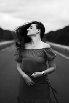 Monochrome portrait of a woman enjoying the breeze on an open road.