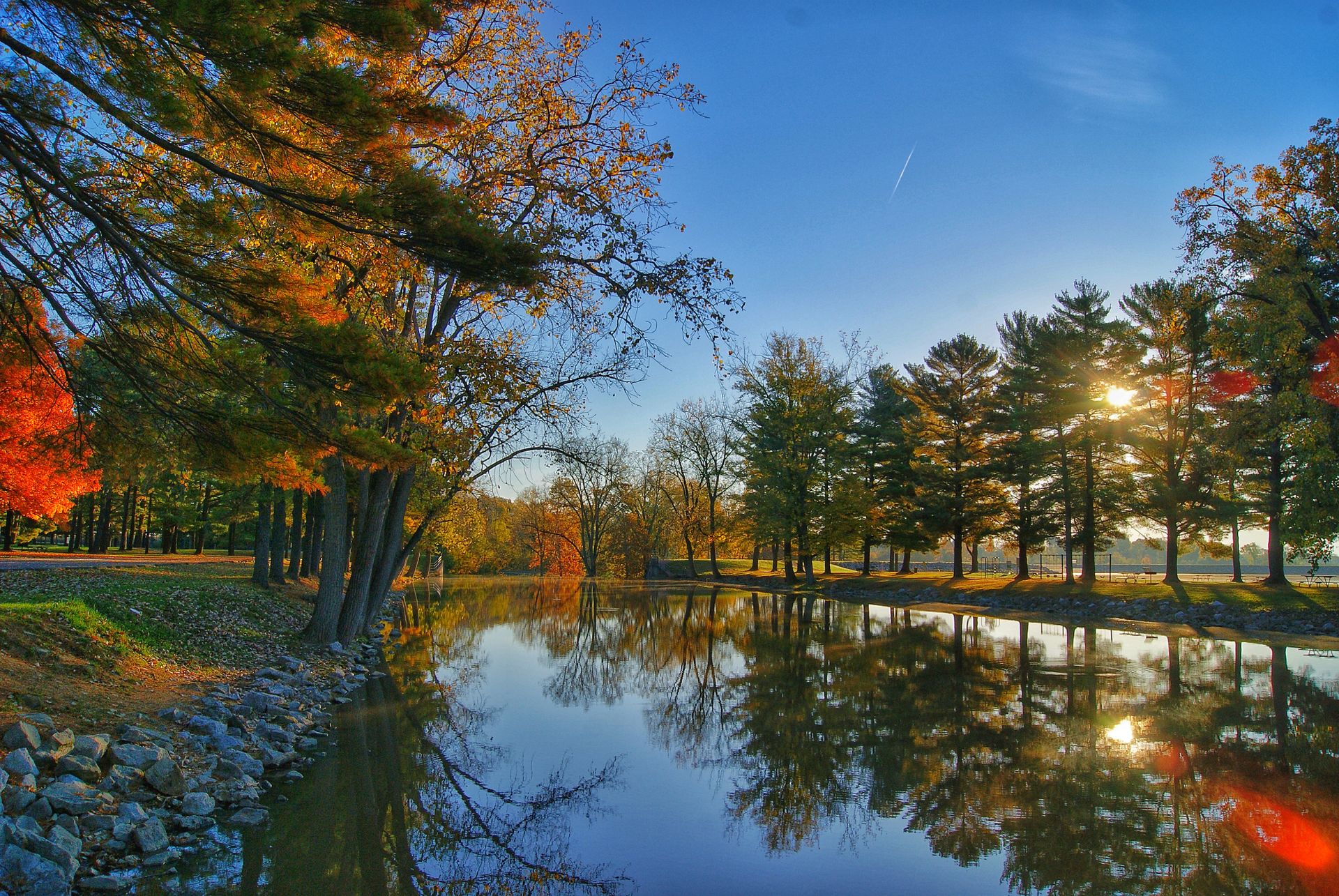 Peaceful autumn landscape of a lake with colorful trees reflecting under morning light.