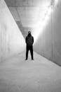 Grayscale Photo of a Man Standing in a Hoodie