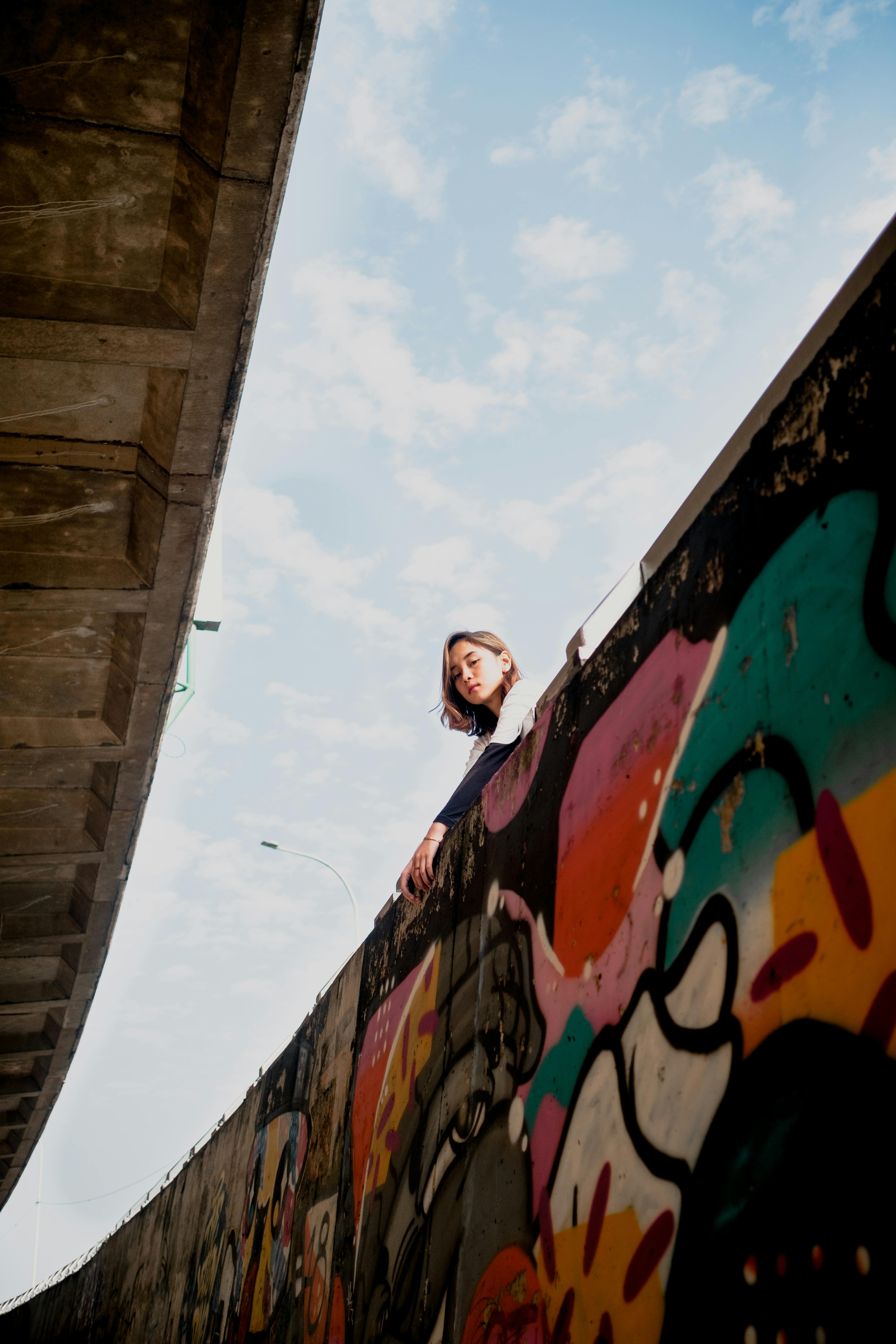 a low angle shot of a woman near the graffiti wall