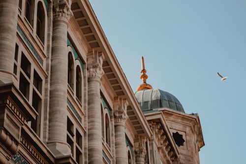 Free Upward view of a historical building with grand marble columns and a blue dome against a clear sky. Stock Photo