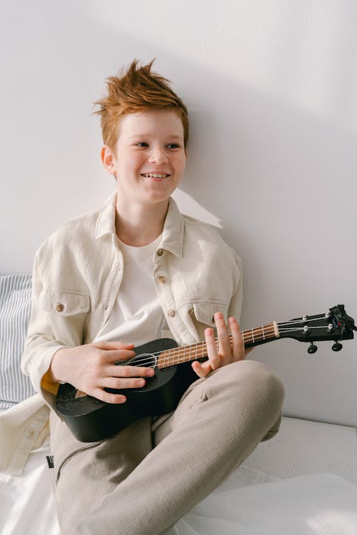 Free A Young Handsome Boy Sitting while Holding His Ukulele Stock Photo