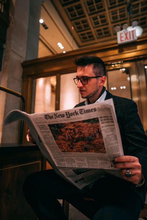 Free Adult man with glasses reading a newspaper indoors, creating a thoughtful and sophisticated scene. Stock Photo