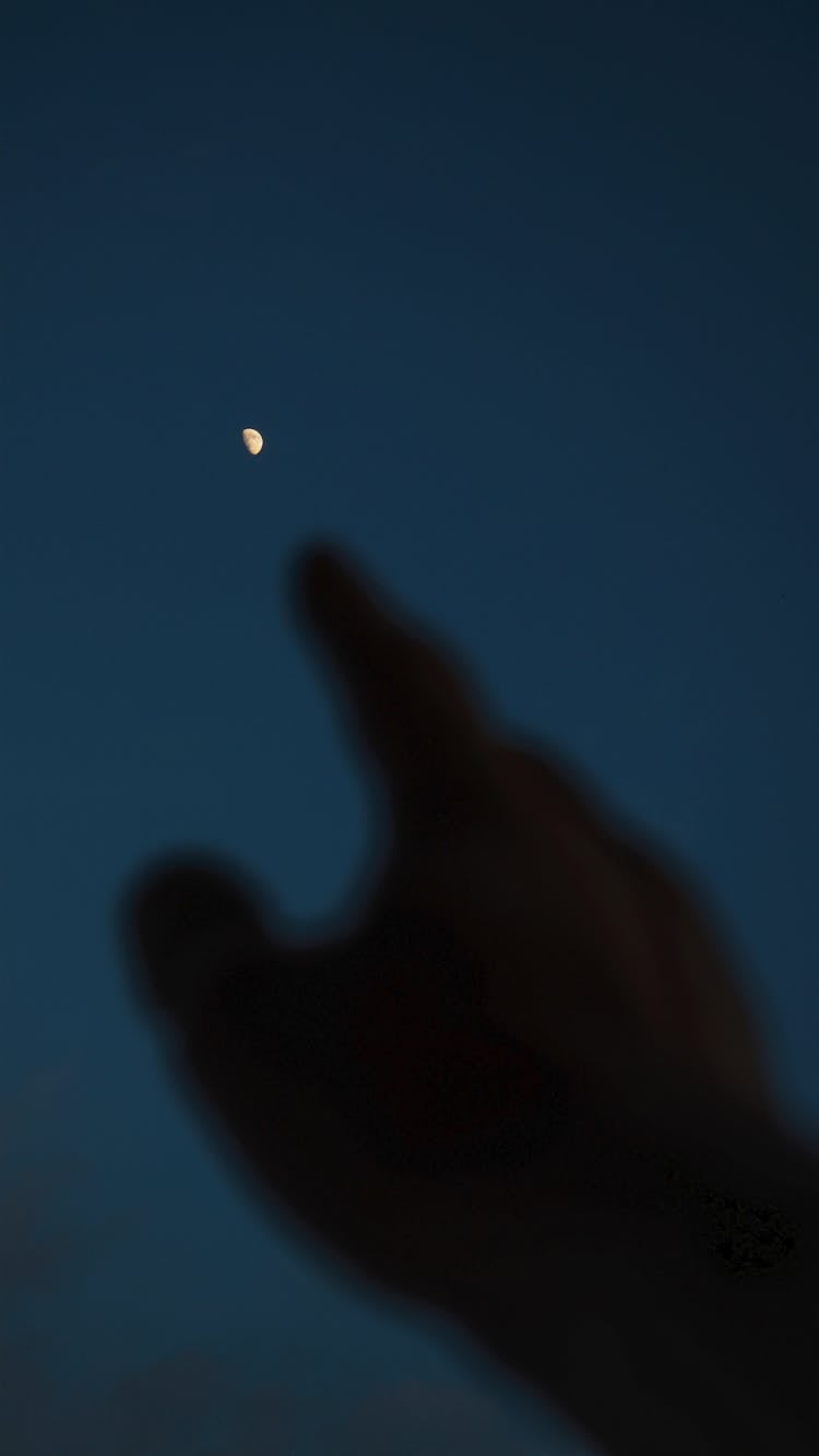 Silhouette Of A Person's Hand Reaching For The Moon