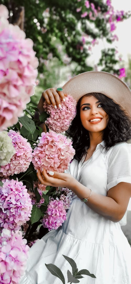 Free Woman in White Dress Holding Pink Flowers Stock Photo