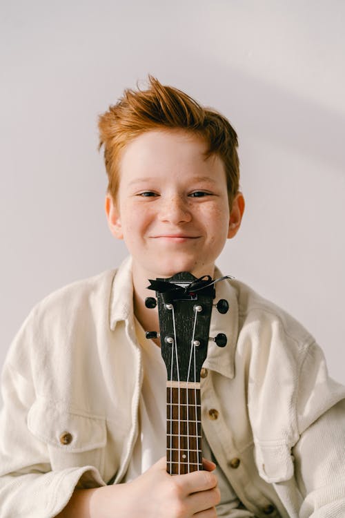 Foto profissional grátis de bonito, garoto, instrumento musical